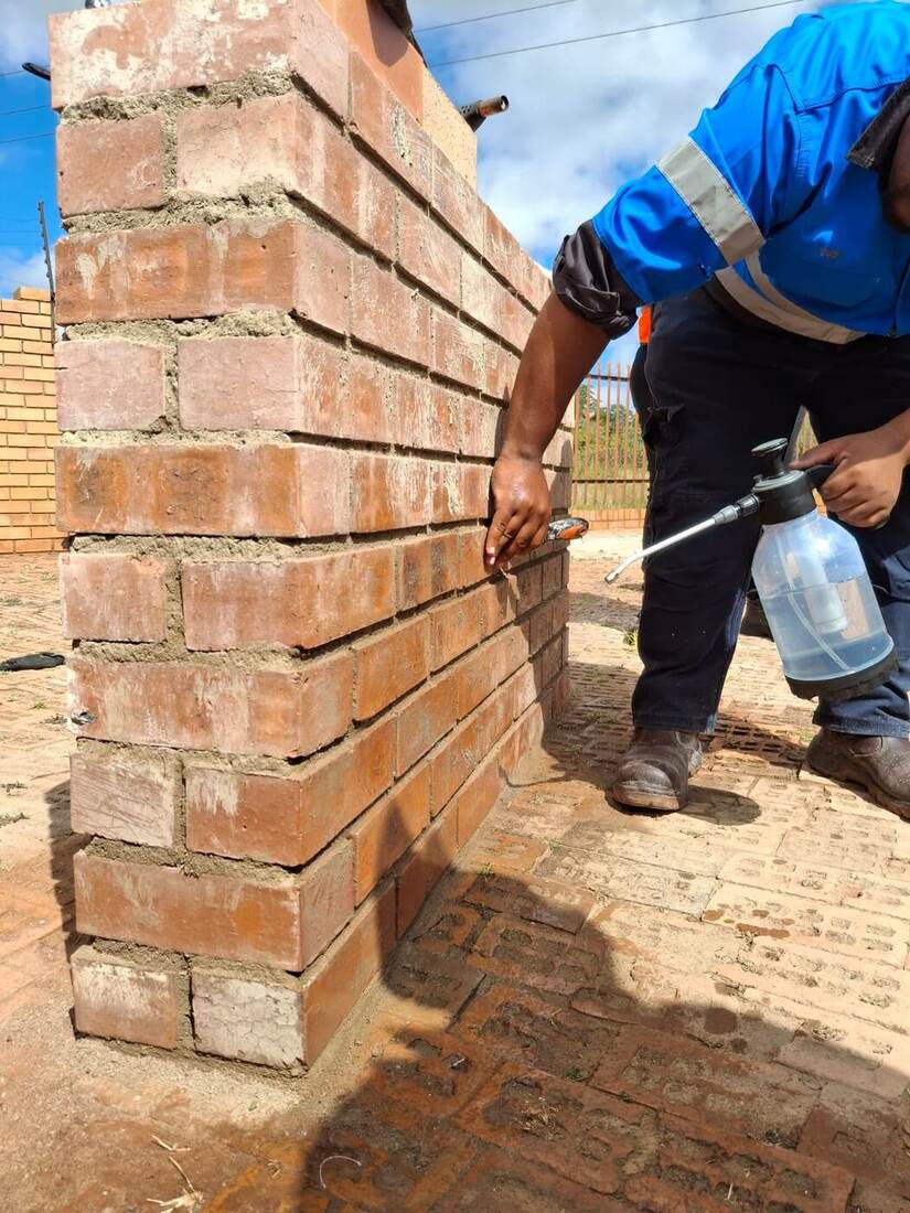Technician applying a cleaning treatment to a facebrick pillar